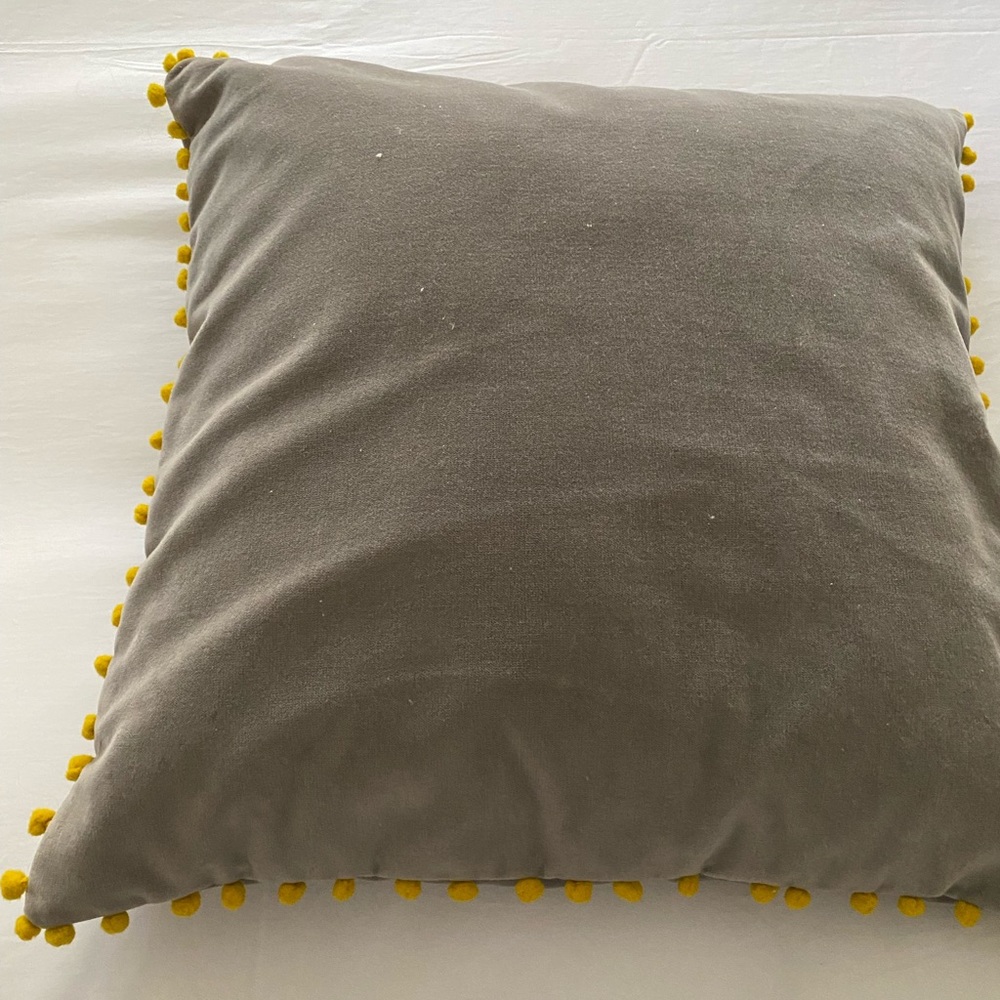 Two hand made grey pillows with yellow Pom poms.